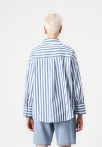 Striped shirt in light blue and white cotton, featuring a classic collar, long sleeves, and a rounded hem with buttoned cuffs.