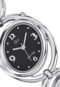 Montre en métal argenté avec un cadran noir. Aiguilles des heures et des minutes argentées, chiffres 3, 6, 9 et 12, et petits points pour les autres heures. Présente un design de bracelet à maillons.