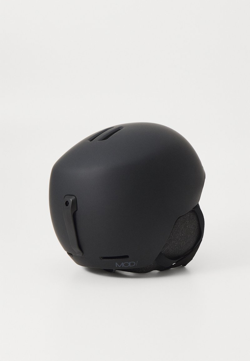 Svart skidhjälm med matt yta, rundad form, ventilationsöppningar på toppen, justerbar spänne på sidan och mjuk innervadd.