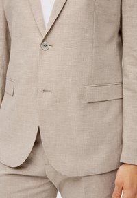 Beige geruite blazer gemaakt van gestructureerde stof, met een enkele knoopsluiting, gesneden revers en twee voorzakken.