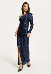 Navy sequin evening dress featuring a one-shoulder design, long sleeve, and a thigh-high slit, with gathered detailing at the waist.