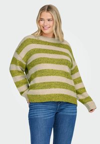 Gebreide trui met groene en beige horizontale strepen, met een textuur afwerking. Het heeft een wijde halslijn en een losse pasvorm. Gecombineerd met blauwe jeans.