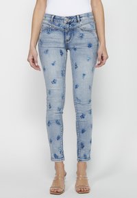 Ljusblå denimjeans med blommönster i nyanser av blått. Slim fit-design med fem fickor och dragkedjestängning.