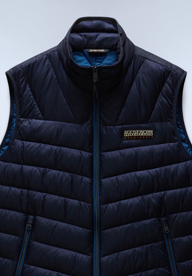 Gilet imbottito blu navy con colletto alto, chiusura frontale con zip, design trapuntato e una piccola patch con logo sul lato sinistro del petto, con rivestimento a contrasto.