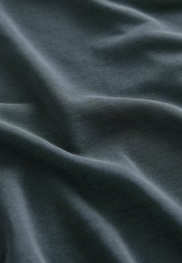Tissu gris foncé avec une texture fine et des plis doux créant des vagues lisses et fluides.