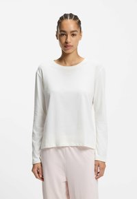 Biały top z długim rękawem wykonany z miękkiego materiału, z okrągłym dekoltem i dyskretnym logo "BOSS" blisko środka. Prosty krój i design.