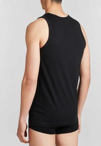 Top nero senza maniche realizzato in cotone, con texture liscia e design aderente, mostrato da dietro.