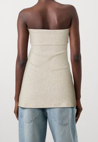 Top strapless beige a costine con un busto aderente, che si allunga fino a una vestibilità più ampia. Abbinato a jeans blu chiaro aww vestibilità ampia.