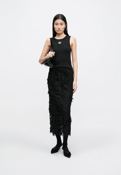 Μαύρη αμάνικη μπλούζα με ριγωτή υφή, συνδυασμένη με φλοράλ δαντελένια μίντι φούστα. Το σύνολο συμπληρώνεται από μαύρες μποτάκια μέχρι τον αστράγαλο και μια μικρή τσάντα.