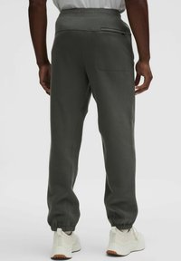 Sötét szürke, lazán illeszkedő melegítőnadrág, rugalmas derékkal, kötött bokákkal és oldzsebből áll. Puha, textúrált anyagból készült.