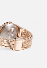 Roségoldene Metalluhr mit einem Netzarmband, ausgestattet mit einem runden Gehäuse und einem polierten Verschluss, der mit "TIMEX" gekennzeichnet ist. Glatte Textur und stromlinienförmiges Design.