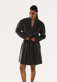 Leopardprint-kjole i mørkegråt stof. Har lange ærmer, en bred krave og et bånd i taljen, med et blødt, tekstureret udseende.