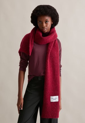 Écharpe en laine cramoisie avec une finition douce et texturée, drapée librement. Dispose d'une étiquette "Marc O'Polo Denim" à une extrémité.