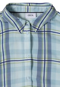 Chemise à carreaux bleu clair avec boutons, rayures vertes, bleu marine et blanches, avec un col pointu et une étiquette de marque "CECIL" à l'intérieur de l'encolure.