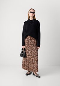 Must be mustrei, mustrei puuvillane kootud kampsun, must nööbiga särk all, pruun leopardimustriga maksikleit, must käekott ja suletud varvaskingad.