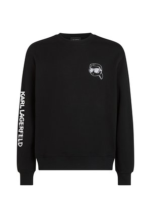 Schwarzer Rundhalsausschnitt-Pullover mit weißem "Karl Lagerfeld"-Text auf dem rechten Ärmel und einem kleinen Cartoon-Gesicht mit Sonnenbrille auf der linken Brust.