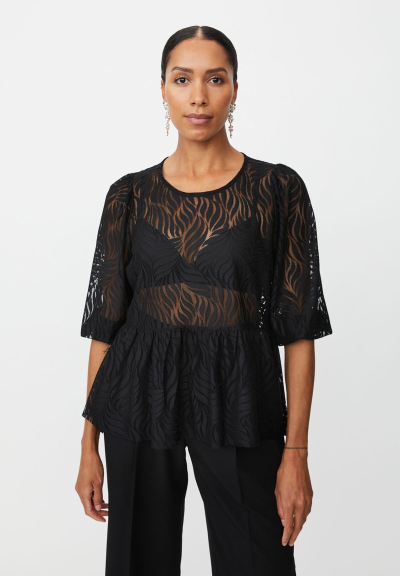 Sort peplum-top med gennemsigtigt stof med blomsterprint, korte puffærmer og rund halsudskærm. Bæres med skræddersyede sorte bukser.