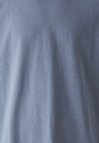Ljusblå t-shirt tillverkad av mjuk bomull, med en slät textur och avslappnad design, med lätt drapering. Inga synliga mönster eller accenter.