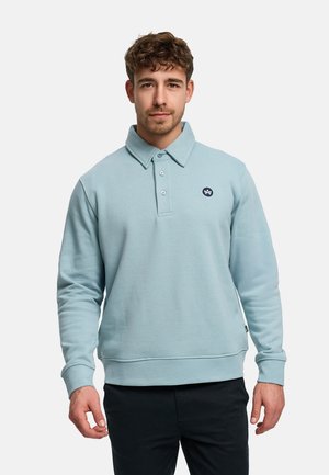 Lyseblå polo-sweatshirt laget av teksturert stoff, med klassisk krage, treknappet stolpe og en liten logo på brystet.