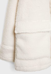 Witte fleecejas met een zachte, getextureerde stof, een omgeslagen kraag en twee zakken aan de voorkant.