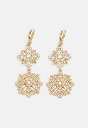 Boucles d'oreilles pendantes ton or avec des motifs floraux complexes et des strass clairs sur deux formes ornementales reliées.