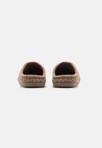 Brune filt tøfler med en blød tekstur, rund form og flade såler. Åben bagdesign for nem påtagning. Minimalistisk æstetik.