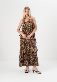 Maxi haljina s uzorkom leoparda s naborima, izrađena od lagane tkanine. Haljina bez naramenica, s lepršavim siluetom i glatkom teksturom.