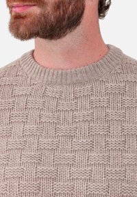 Pull beige en tricot avec un motif texturé en nid d'abeille, col rond côtelé et fil de laine de poids moyen. Coutures minimales visibles.