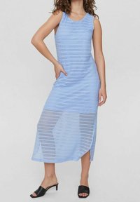 Maxi dress azzurro chiaro realizzato in un tessuto testurizzato e traspirante con strisce orizzontali e spacchi laterali, abbinato a tacchi open-toe neri.