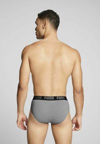 Graue Baumwollunterhose mit einem schwarzen elastischen Bund, der das "PUMA"-Logo zeigt, von hinten betrachtet, wobei Passform und Design hervorgehoben werden.