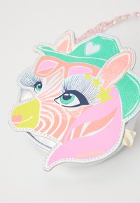 Zebraformad kompakt med glänsande detaljer, pastellfärger, glittrande inslag, en distinkt grön hatt och överdimensionerade ögon med stjärnprydnader.