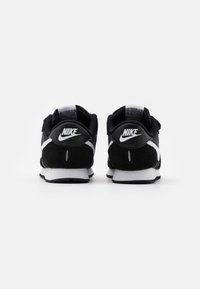 Mustat Nike-tennarit, joissa on nahka- ja verkkomateriaali, valkoiset yksityiskohdat ja klassinen muotoilu, sekä pehmeät pohjat mukavuutta varten.