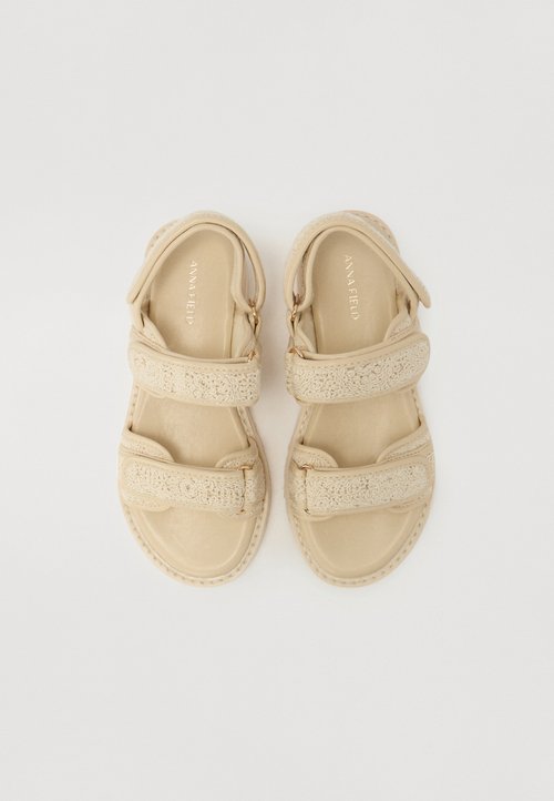 Sandalias beige con dos correas anchas, con un diseño texturizado. Plantilla suave, detalles de costura y una forma de punta redonda.