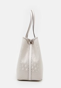 Sac à main blanc à perforations en forme de seau, avec deux poignées et une fermeture éclair. Garniture en cuir lisse le long des bords et de la base.