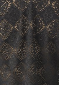 Black lace fabric featuring a diamond and floral pattern, with a soft texture and delicate open weave, layered over a neutral base.