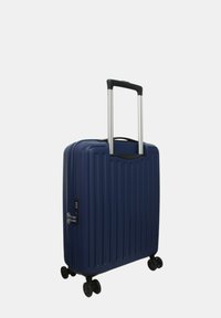 Valigia rigida navy con scanalature verticali, manico telescopico, cerniera e lucchetto a combinazione, montata su quattro ruote piroettanti per la mobilità.