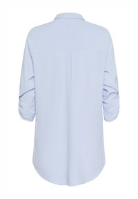 Vaaleansininen paita, pitkät hihat käärittynä, pehmeä materiaali, selän kaarrokeommel, kaareva helma, ei näkyviä kuvioita tai koristeosia.