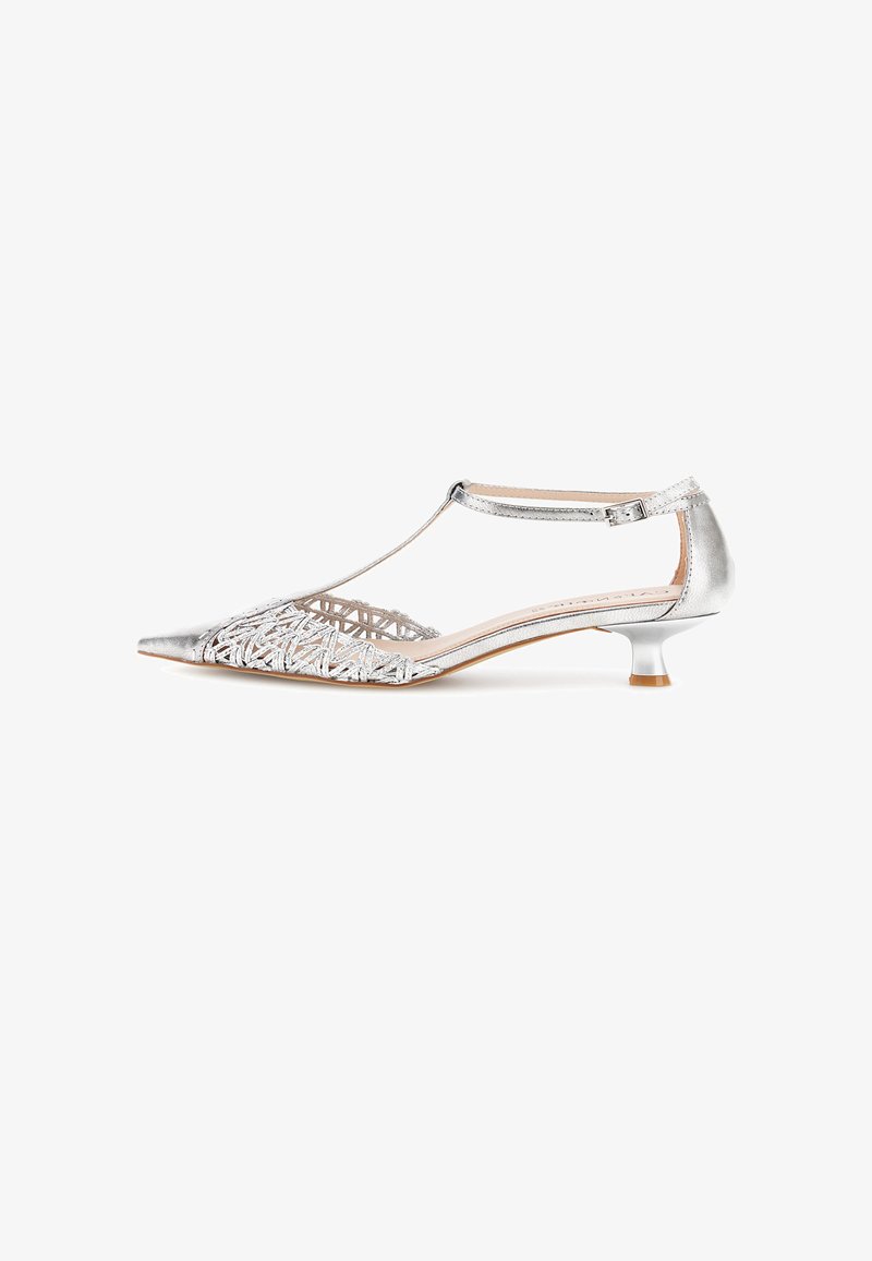 Zapato plateado de tacón kitten con tira en T, punta puntiaguda y detalle lateral abierto tejido sobre fondo blanco.