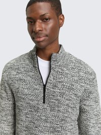 Grijze gebreide pullover met een kwartritssluiting bij de hals, voorzien van een geaccentueerd patroon. De stof lijkt dik en gezellig, in contrast met een wit ondershirt.