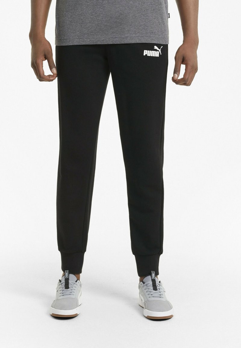 Black sweatpants with ribbed cuffs, featuring a white Puma logo on the left thigh. Made of soft, textured material.