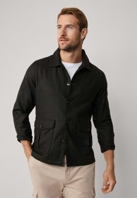 Donkergrijze button-up jas met een spread collar, twee voorzakken en opgerolde mouwen. Gemaakt van gestructureerde stof, met een getailleerd silhouet.