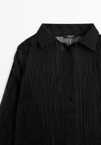 Schwarze, zerknitterte Button-up-Bluse mit spitzem Kragen, ausgestattet mit schwarzen Knöpfen und einem strukturierten, leichten Stoffdesign.