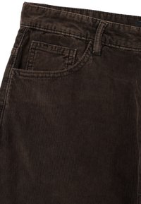 Bruine corduroy broek met verticale ribbels, voorzien van een voorzak en een stevige tailleband. De stof heeft een zachte textuur en een gedempte afwerking.