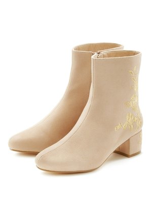 Beżowe botki za kostkę wykonane z zamszu, z kwadratowym noskiem, obcasem typu klocek i żółtym kwiatowym haftem po zewnętrznej stronie. Zapięcie na suwak.