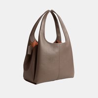 Brown leather handbag with dual handles and a subtle tag, featuring a smooth, slightly textured surface and a structured, spacious design.