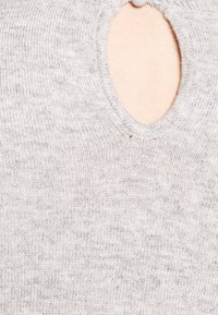 Suéter gris con un detalle de corte ovalado en el escote. Textura de punto suave con un tejido fino, que presenta una sutil variación de color.