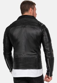 Zwarte leren motorjack met geribbelde details op de schouders en zijkanten, ritsmanchetten en een klassiek kraagontwerp.
