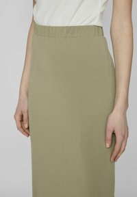 Falda verde olivo, hasta la rodilla, hecha de un tejido suave y elástico con una cinturilla elástica; textura suave y diseño sencillo.