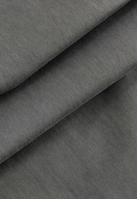 Grauer Baumwollstoff mit glatter Textur, der gefaltete Lagen aufweist, die sein feines Gewebe und die konsistente Farbe durchgängig betonen.
