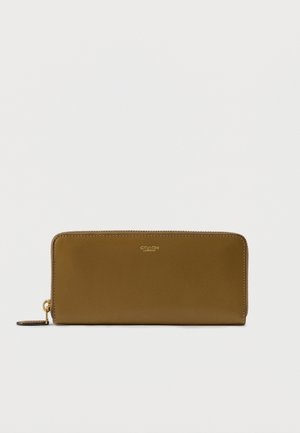 Portofel dreptunghiular din piele maro deschis cu fermoar pe margine, fermoar cu nuanță aurie și logo mic „Coach New York” embossat centrat pe față.